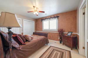 Bedroom with light carpet, a textured ceiling, and ceiling fan