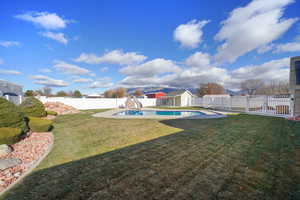 View of yard featuring a fenced in pool and a storage shed