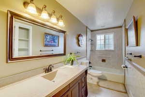 Full bathroom featuring tile patterned floors, vanity, a textured ceiling, tiled shower / bath combo, and toilet