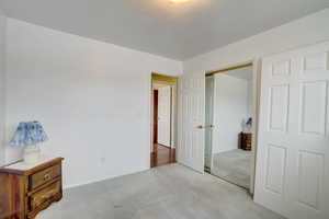 Unfurnished bedroom with light carpet, a closet, and a textured ceiling