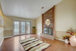 Living room with lofted ceiling, a fireplace, and light hardwood / wood-style flooring