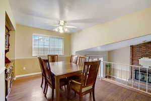 Dining area with hardwood / wood-style flooring, ceiling fan, lofted ceiling, and a brick fireplace