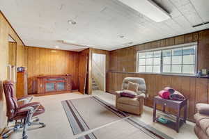 Sitting room with wood walls and light colored carpet