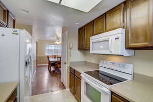 Kitchen with light wood-type flooring, a textured ceiling, white appliances, and ceiling fan