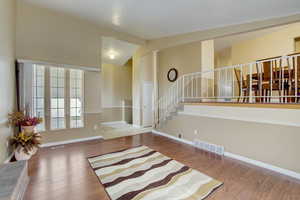 Empty room featuring vaulted ceiling and hardwood / wood-style flooring