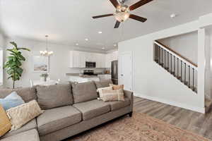 Living room featuring hardwood / wood-style floors, ceiling fan with notable chandelier, and sink