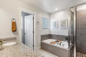 Bathroom with tile patterned floors, vanity, and separate shower and tub