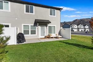 Back of property featuring a lawn, a patio area, and a mountain view