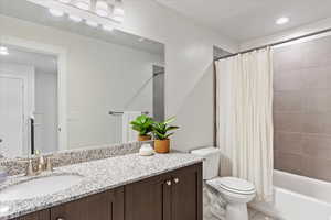 Full bathroom with tile patterned flooring, vanity, shower / tub combo, and toilet