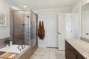 Bathroom with tile patterned floors, vanity, and separate shower and tub