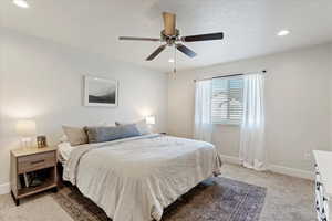 Carpeted bedroom featuring ceiling fan and a textured ceiling