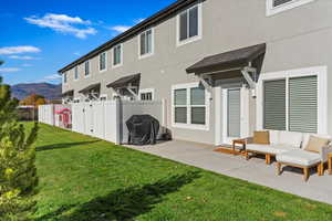 Rear view of property featuring a lawn, a mountain view, and a patio