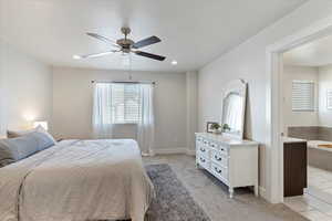 Carpeted bedroom featuring ceiling fan and ensuite bathroom