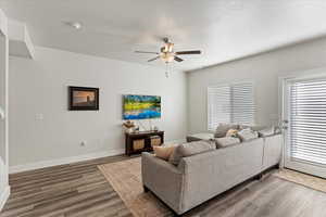 Living room with ceiling fan, hardwood / wood-style floors, and a textured ceiling