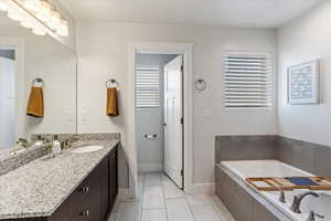 Bathroom with vanity, a relaxing tiled tub, and tile patterned floors