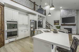 Kitchen with white cabinets, a kitchen breakfast bar, pendant lighting, and sink