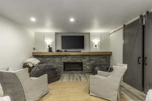 Living room featuring a textured ceiling, a barn door, a fireplace, and light hardwood / wood-style flooring