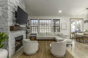 Living room with a fireplace, french doors, and light wood-type flooring