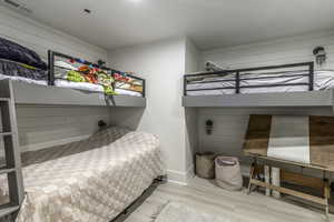 Bedroom with wood walls and wood-type flooring