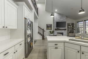 Kitchen featuring stainless steel fridge, light hardwood / wood-style floors, sink, and hanging light fixtures