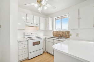 Kitchen featuring white cabinetry, sink, ceiling fan, white electric stove, and light wood-type flooring