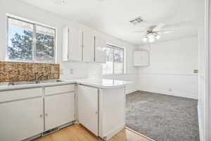 Kitchen featuring white cabinets, ceiling fan, light wood-type flooring, and sink