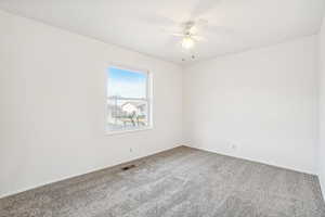 Spare room featuring carpet flooring and ceiling fan