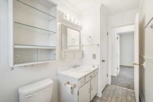 Bathroom with vanity, toilet, and ornamental molding