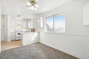 Kitchen featuring white cabinetry, ceiling fan, white range with electric stovetop, kitchen peninsula, and light hardwood / wood-style floors