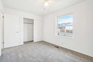 Unfurnished bedroom featuring carpet flooring, ceiling fan, and a closet