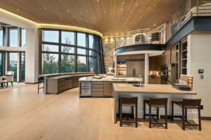 Kitchen with a towering ceiling, wood ceiling, a breakfast bar, light wood finished floors, and a peninsula