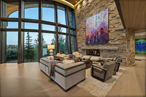 Living room with a high ceiling, wood finished floors, and a stone fireplace