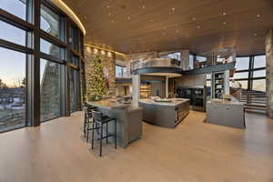 Kitchen with sink, a center island with sink, wooden ceiling, a high ceiling, and light hardwood / wood-style floors