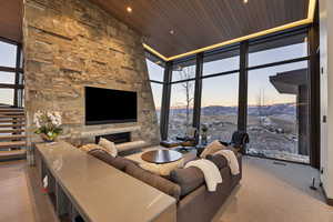 Living room with floor to ceiling windows, wooden ceiling, high vaulted ceiling, a fireplace, and hardwood / wood-style flooring