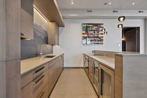 Kitchen featuring pendant lighting, beverage cooler, black electric stovetop, and sink