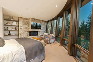 Carpeted bedroom featuring a stone fireplace
