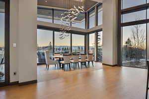 Dining room with a towering ceiling, light hardwood / wood-style flooring, and a notable chandelier