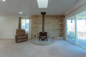 Unfurnished room featuring a wood stove, carpet floors, brick wall, and ornamental molding