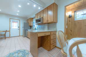 Kitchen with sink, white refrigerator, track lighting, wooden walls, and light tile patterned flooring