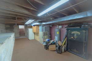 Basement with white refrigerator, gas water heater, and heating unit