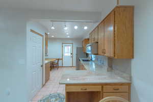 Kitchen with kitchen peninsula, refrigerator, sink, and rail lighting