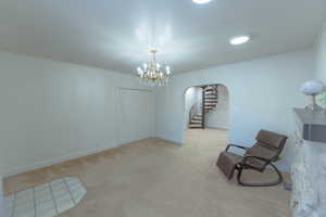 Unfurnished room with a notable chandelier, crown molding, and light carpet