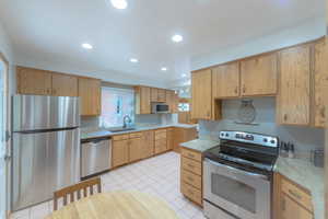 Kitchen with light brown cabinets, stainless steel appliances, light tile patterned floors, and sink