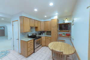 Kitchen featuring light brown cabinetry, stainless steel range with electric cooktop, and light tile patterned floors