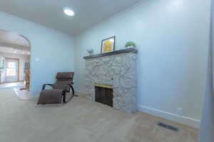 Sitting room featuring a stone fireplace, carpet, and ornamental molding