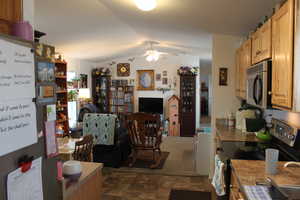 Kitchen featuring ceiling fan, light brown cabinetry, vaulted ceiling, and appliances with stainless steel finishes