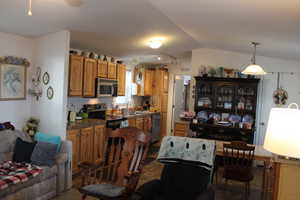 Kitchen featuring sink, pendant lighting, lofted ceiling, and appliances with stainless steel finishes