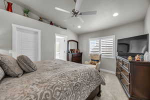 Carpeted bedroom featuring ceiling fan and lofted ceiling