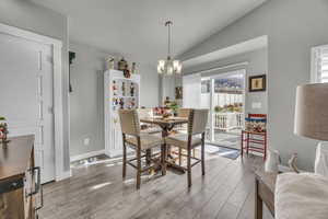 Dining area featuring wood-type flooring, vaulted ceiling, and a notable chandelier