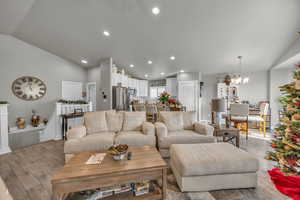 Living room featuring light hardwood / wood-style floors, lofted ceiling, and a chandelier